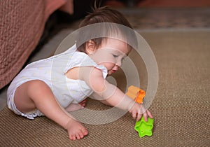 lifestyle home portrait of adorable and beautiful Asian Caucasian mixed baby girl playing on the floor with color blocks excited