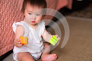 lifestyle home portrait of adorable and beautiful Asian Caucasian mixed baby girl playing on the floor with color blocks excited