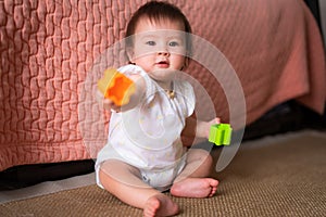 lifestyle home portrait of adorable and beautiful Asian Caucasian mixed baby girl playing on the floor with color blocks excited