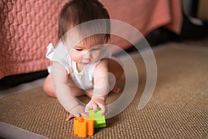 lifestyle home portrait of adorable and beautiful Asian Caucasian mixed baby girl playing on the floor with color blocks excited