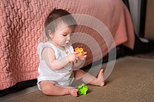 lifestyle home portrait of adorable and beautiful Asian Caucasian mixed baby girl playing on the floor with color blocks excited