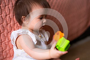 lifestyle home portrait of adorable and beautiful Asian Caucasian mixed baby girl playing on the floor with color blocks excited