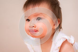 lifestyle home portrait of adorable and beautiful Asian Caucasian mixed baby girl sticking her tongue out in adorable face