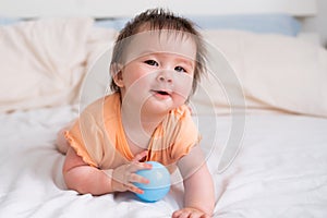 lifestyle home portrait of happy and beautiful 8 months old baby girl mixed race Asian Caucasian playing with ball cheerful on bed