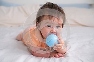 lifestyle home portrait of happy and beautiful 8 months old baby girl mixed race Asian Caucasian playing with ball cheerful on bed