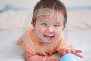 lifestyle home portrait of happy and beautiful 8 months old baby girl mixed race Asian Caucasian playing with ball cheerful on bed