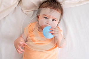 lifestyle home portrait of happy and beautiful 8 months old baby girl mixed race Asian Caucasian playing with ball cheerful on bed