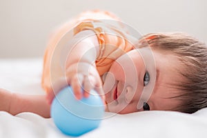 lifestyle home portrait of happy and beautiful 8 months old baby girl mixed race Asian Caucasian playing with ball cheerful on bed