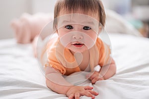 lifestyle home portrait of happy and beautiful 8 months old baby girl mixed race Asian Caucasian playing cheerful on bed exploring