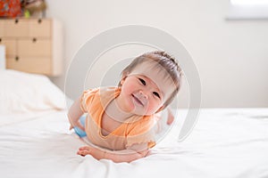 lifestyle home portrait of happy and beautiful 8 months old baby girl mixed race Asian Caucasian playing cheerful on bed exploring