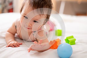 lifestyle home portrait of sweet and adorable mixed ethnicity Asian Caucasian baby girl playing with color blocks on bed excited