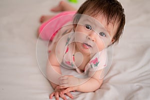 lifestyle home portrait of sweet and adorable mixed ethnicity Asian Caucasian baby girl playing with color blocks on bed excited