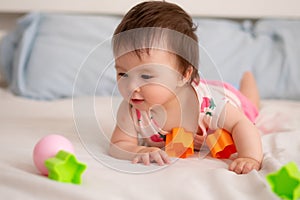 lifestyle home portrait of sweet and adorable mixed ethnicity Asian Caucasian baby girl playing with color blocks on bed excited