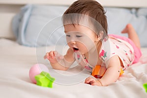 lifestyle home portrait of sweet and adorable mixed ethnicity Asian Caucasian baby girl playing with color blocks on bed excited