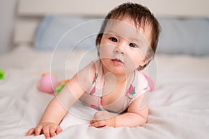 lifestyle home portrait of sweet and adorable mixed ethnicity Asian Caucasian baby girl playing with color blocks on bed excited