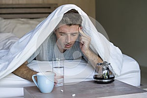 Lifestyle home portrait of young exhausted and wasted man waking up suffering headache and hangover after drinking alcohol at nigh photo