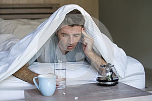 Lifestyle home portrait of young exhausted and wasted man waking up suffering headache and hangover after drinking alcohol at nigh