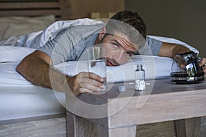 Lifestyle home portrait of young exhausted and wasted man waking up suffering headache and hangover after drinking alcohol at nigh