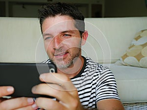 Lifestyle home portrait of young happy and attractive 30s man using internet dating app or messaging social media on mobile phone