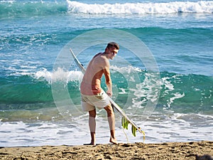 A surfer getting ready for the surf. .Man is applying wax to surfboard shortboard on vacation photo