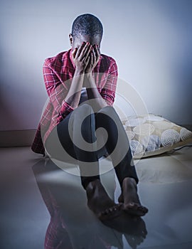 Lifestyle indoors portrait of young sad and depressed black afro American woman sitting at home floor feeling desperate and worrie