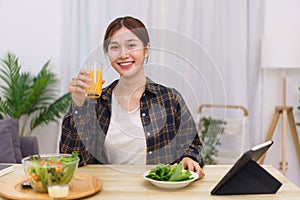 Lifestyle in living room concept, Asian woman drinking orange juice and eating vegetable salad