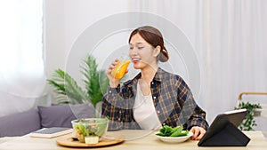 Lifestyle in living room concept, Asian woman drinking orange juice and eating vegetable salad