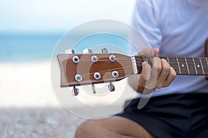 Lifestyle man. Close up handsome man playing classic guitar sitting on the beach in vacations,summer.