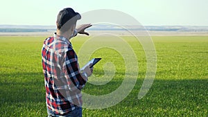 lifestyle man farmer red neck with a digital tablet walks on a green field. eco smart farming agriculture concept. male