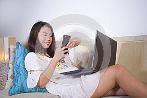 Lifestyle natural portrait of young pretty and happy Asian Korean student woman at home working on laptop computer enjoying textin