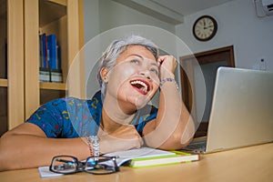 Lifestyle office portrait of attractive and happy successful middle aged Asian woman working at laptop computer desk smiling