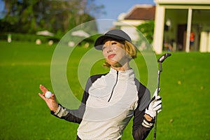 Lifestyle outdoors portrait of young beautiful and happy woman at playing golf holding ball and putter club smiling cheerful in st