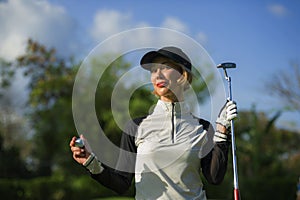 Lifestyle outdoors portrait of young beautiful and happy woman at playing golf holding ball and putter club smiling cheerful in st