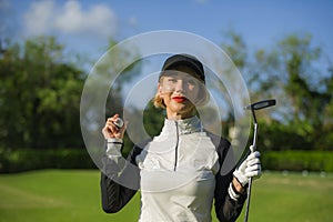 Lifestyle outdoors portrait of young beautiful and happy woman at playing golf holding ball and putter club smiling cheerful in st