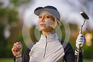 Lifestyle outdoors portrait of young beautiful and happy woman at playing golf holding ball and putter club smiling cheerful in st