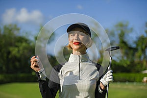 Lifestyle outdoors portrait of young beautiful and happy woman at playing golf holding ball and putter club smiling cheerful in st