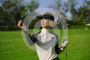 Lifestyle outdoors portrait of young beautiful and happy woman at playing golf holding ball and putter club smiling cheerful in st