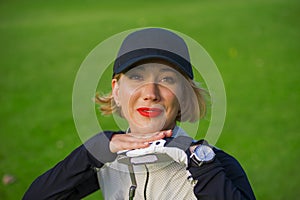 Lifestyle outdoors portrait of young beautiful and happy woman at playing golf leaning sweet on club smiling cheerful in stylish g