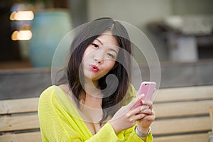 Lifestyle outdoors urban portrait of young attractive and beautiful Asian Japanese woman enjoying using internet social media app