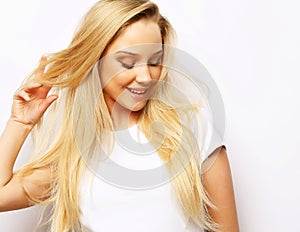 lifestyle and people concept - Beautiful happy blond girl touches her hair. Casual clothes. White background.