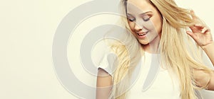 Lifestyle and people concept - Beautiful happy blond girl touches her hair. Casual clothes. White background.Close up.