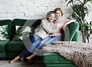 Lifestyle and people concept - Beautiful senior mom and her adult daughter are hugging, looking at camera and smiling.