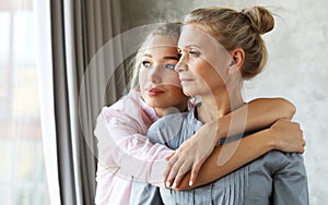 Lifestyle and people concept - beautiful senior mom and her adult daughter are hugging, looking at camera and smiling.