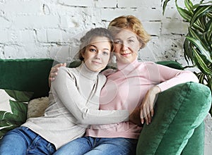 Lifestyle and people concept - Beautiful senior mom and her adult daughter are hugging, looking at camera and smiling.