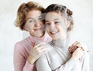 Lifestyle and people concept - Beautiful senior mom and her adult daughter are hugging, looking at camera and smiling,