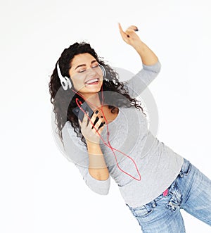 Lifestyle and people concept: Beautiful young woman in headphones listening to music standing on white background