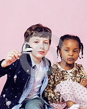 Lifestyle people concept: diverse nation children playing together, caucasian boy with african little girl holding candy