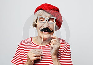 Lifestyle and people concept: funny grandmother with fake mustache and glasses