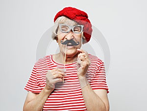 Lifestyle and people concept: funny grandmother with fake mustache and glasses, laughs and prepares for party