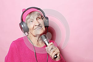 Lifestyle and people concept: Funny old lady listening music with headphones and singing with mic